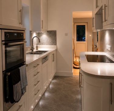 Kitchen with white cabinets, dark tiled floor, built-in double oven, fitted in Cowley.