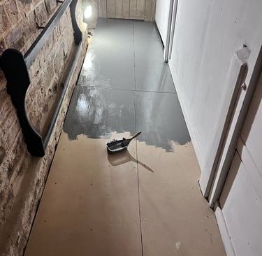 Bathroom floor mid-install showing plumbing and unfinished surfaces.