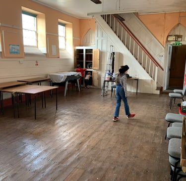 Large open hall mid-renovation with tools and furniture pushed aside.