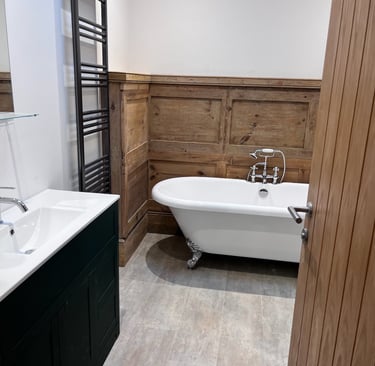 Finished bathroom with freestanding bath and wood-panelled walls.