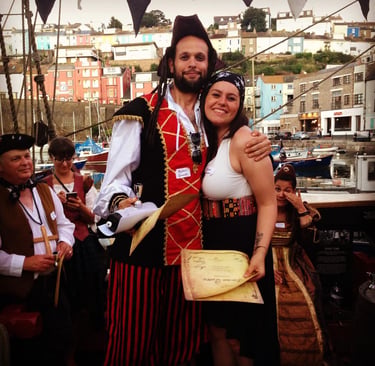 a man and a woman hug. both are dressed as pirates for a pirate themed murder mystery party