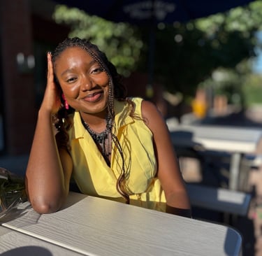 Iheoma Uzomba in yellow dress smiling.