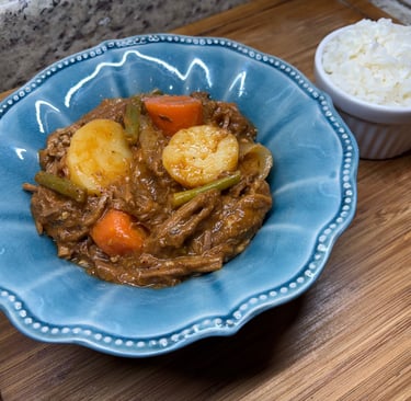 Slow-cooked beef stew with potatoes and carrots in a blue bowl served with a side of white rice.