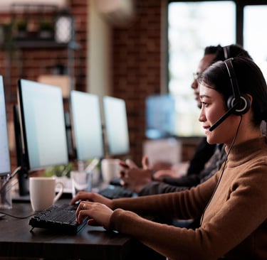Call center agent using headset and computer in a modern customer support office