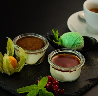 Tiramisu- und Panna-Cotta-Desserts in Gläsern serviert mit Minzeis und Espresso.
