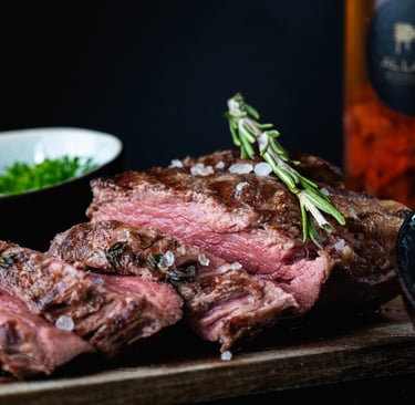 Geschnittenes medium-rare Ribeye-Steak mit Meersalz und Rosmarin auf Holzbrett.