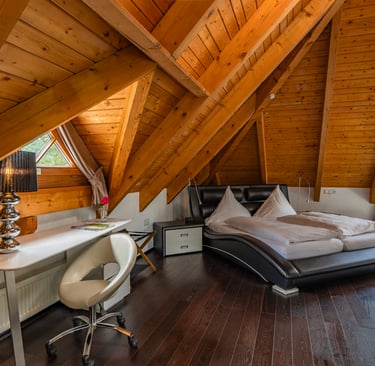 Modern eingerichtetes Hotelzimmer im Dachgeschoss mit Holzarchitektur und natürlichem Licht.