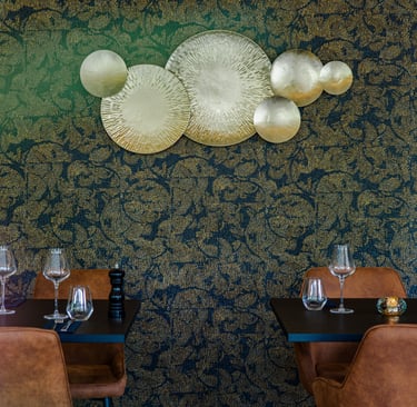 Elegante Restauranttische mit goldener Wandkunst und blauer Blumentapete.