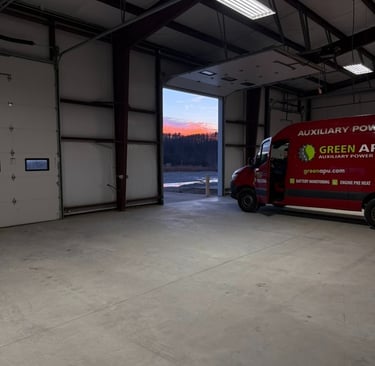Red Green APU auxiliary power service van parked in a large industrial warehouse garage at sunset.