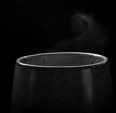 Steam rising from a dark ceramic cup against a black background