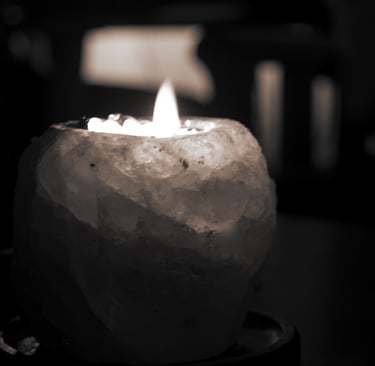 Lit candle in a rough crystal holder with soft light in a dark setting