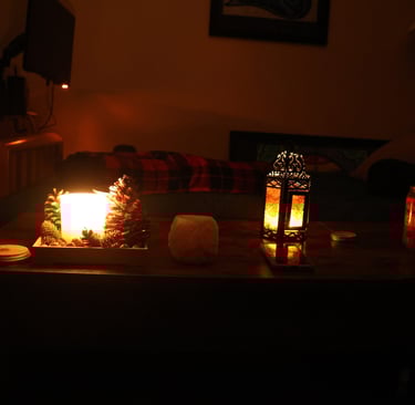 Low light candlelit living room with candles glowing on a wooden table and a sofa in the background.