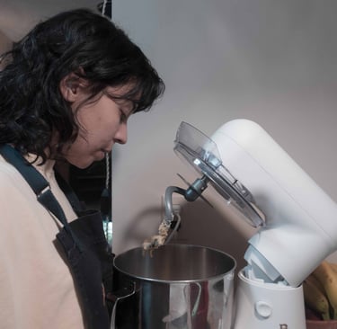 A person using a stand mixer to mix dough in a bowl on a kitchen counter at home.