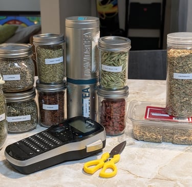 Open cardboard box containing several plastic bags filled with dried herbs and tea ingredients.