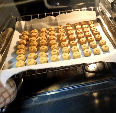 Small shaped cookies on a parchment-lined tray being placed into the oven