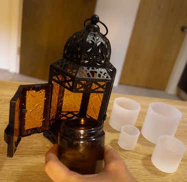 Candle lantern with amber glass panels and silicone molds on a wooden table.