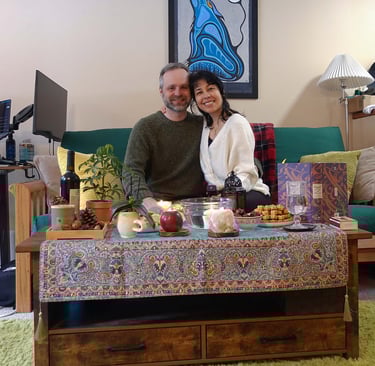 Couple sitting on a couch behind a decorated table, smiling at the camera