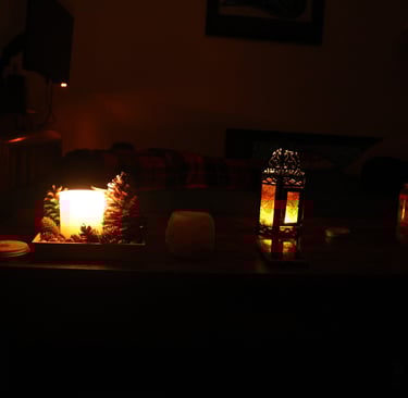 Low light candlelit living room with candles glowing on a wooden table and a sofa in the background.
