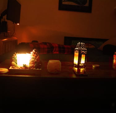 Low light candlelit living room with candles glowing on a wooden table and a sofa in the background.