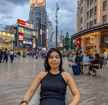 Woman sitting in a public square in downtown Osaka as evening crowds gather around the city center.