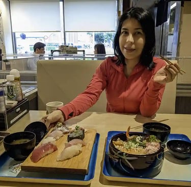 Woman eating sushi and noodle soup at a restaurant table