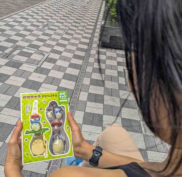 Woman holding a Studio Ghibli souvenir featuring Totoro characters while exploring Osaka, Japan.