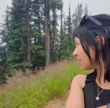 Woman looking across a smoky mountain landscape with evergreen trees in Big White, British Columbia.