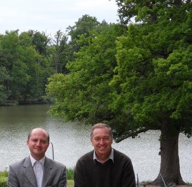 Maitre Pistone et Maître Gestat de Garambé devant lac et paysage arboré.