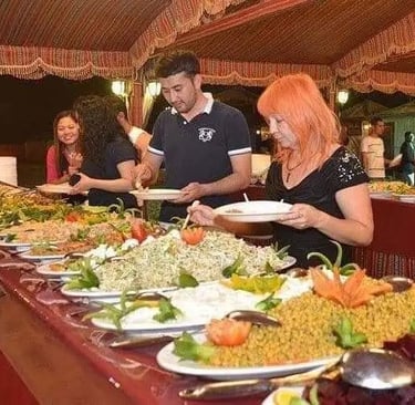 Tourists enjoying a buffet dinner at a Dubai desert safari camp