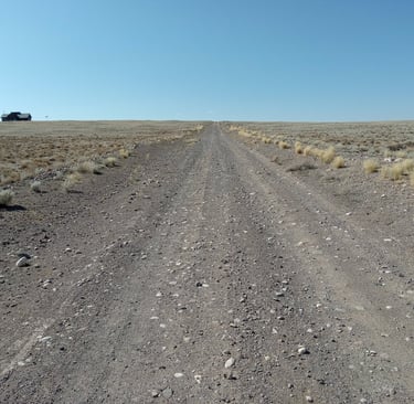 a dirt road with a car parked on the side of the road