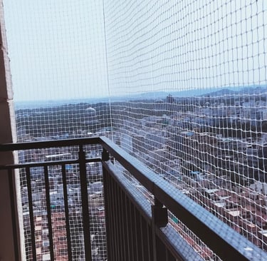 Technician from Arjilli Enterprises fitting a safety net on a balcony railing.