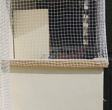 Worker carefully installing a balcony safety net on a high-rise building in Nungabakkam.