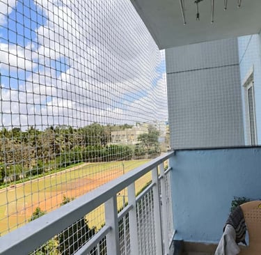 Side view of a balcony safety net with sunlight filtering through, emphasizing the net’s fine mesh.