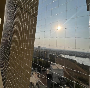 Evening view of a balcony with safety net installed, softly lit by warm indoor lights.