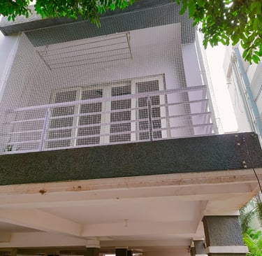 Evening view of a balcony with safety netting softly lit by ambient city lights in Sholinganallur.