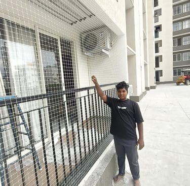 A happy family enjoying their balcony safely enclosed with Arjilli Safety Nets under a bright sky.