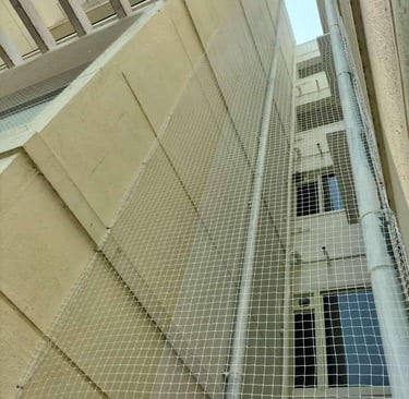 Technician carefully installing a pigeon net on a balcony railing in Chennai.