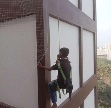 Technician carefully installing a balcony safety net on a residential building