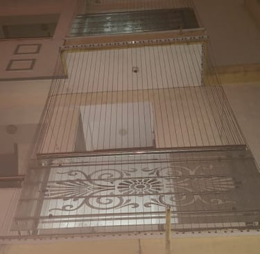 Installation process showing workers fitting anti-pigeon nets on a residential window.