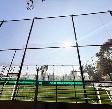 Wide shot of a baseball field with new protective nets installed behind home plate, with players pra