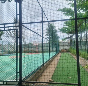 Workers carefully fitting sports nets on a rooftop terrace under a clear blue sky.