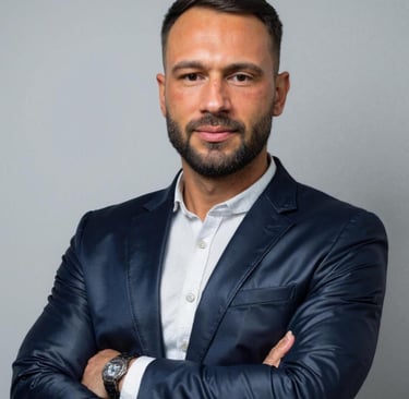 Professional businessman with a beard wearing a navy blue blazer and white shirt.