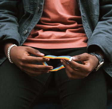 A person holding a rainbow pride wristband, representing LGBTQ+ identity and diversity.