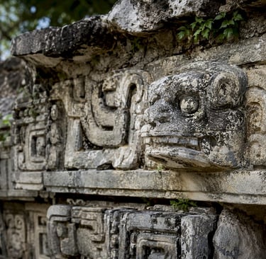 Ancient Mayan stone carvings and jaguar head sculpture at the archaeological ruins of Chichen Itza.