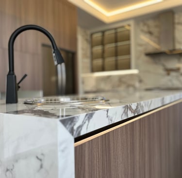 Modern luxury kitchen island featuring white marble countertops and a sleek matte black faucet.