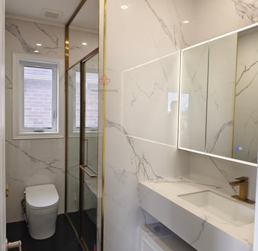 Luxurious white marble bathroom with a frameless shower, modern vanity with gold fixtures, and sleek smart toilet.