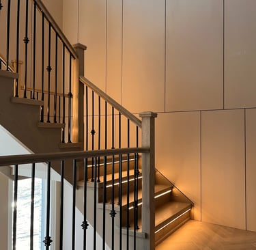 Modern interior oak staircase with LED step lighting and elegant black iron balusters.