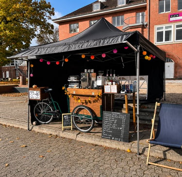 Schwarzes Eventzelt mit Kaffeefahrrad, Kreidetafel-Menü und Lichterkette.
