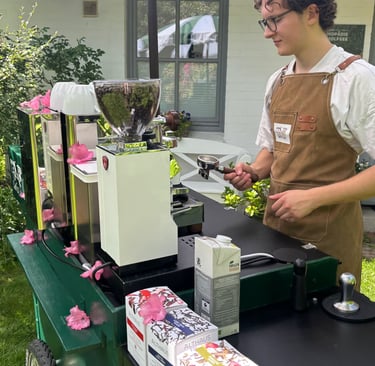 Barista mit Schürze bereitet Kaffee mit Siebträger an Kaffeemühle zu.