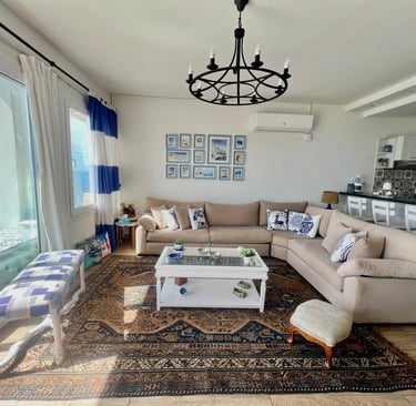 Modern seaside living room with a beige sectional sofa, vintage Persian rug, and ocean view balcony.